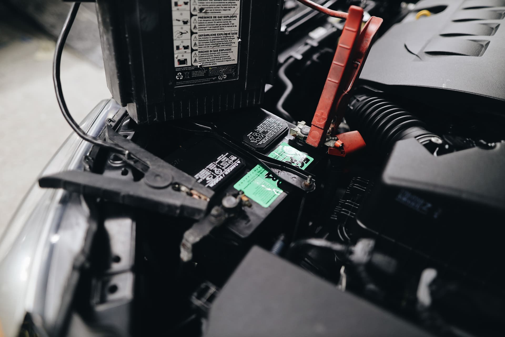 Charger clamps connected to a car battery in a garage