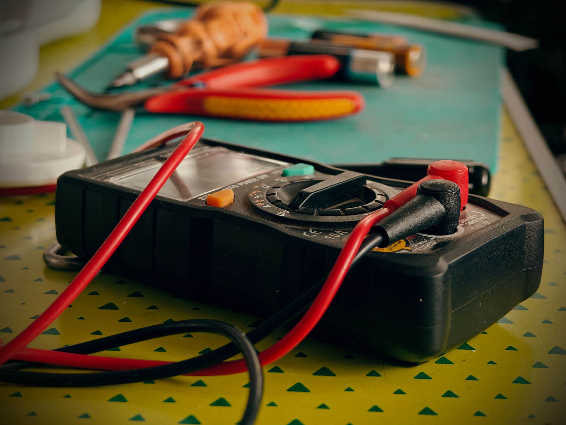 A multimeter and tools on a workbench