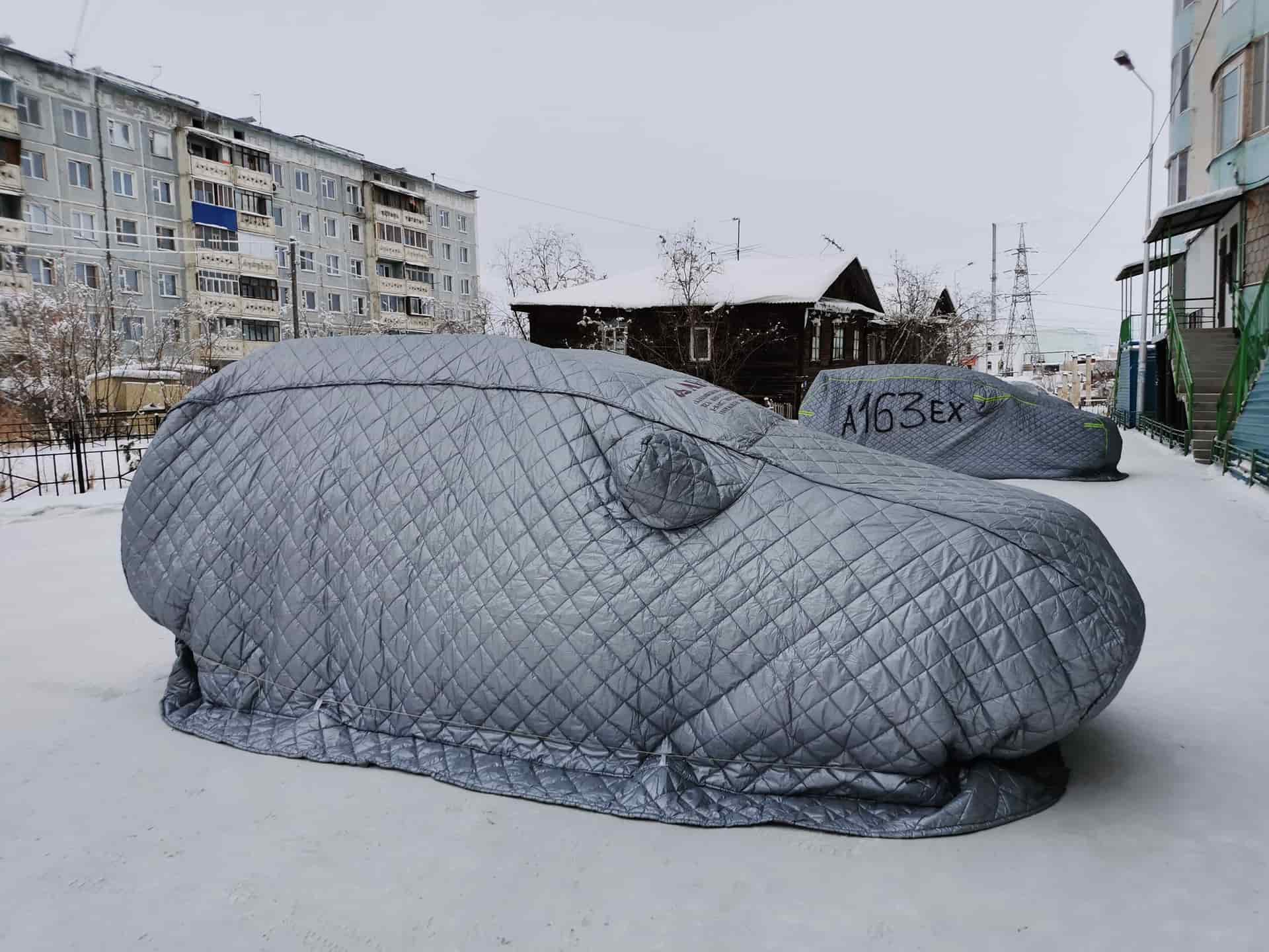 Cars parked under covers on a snowy street in winter