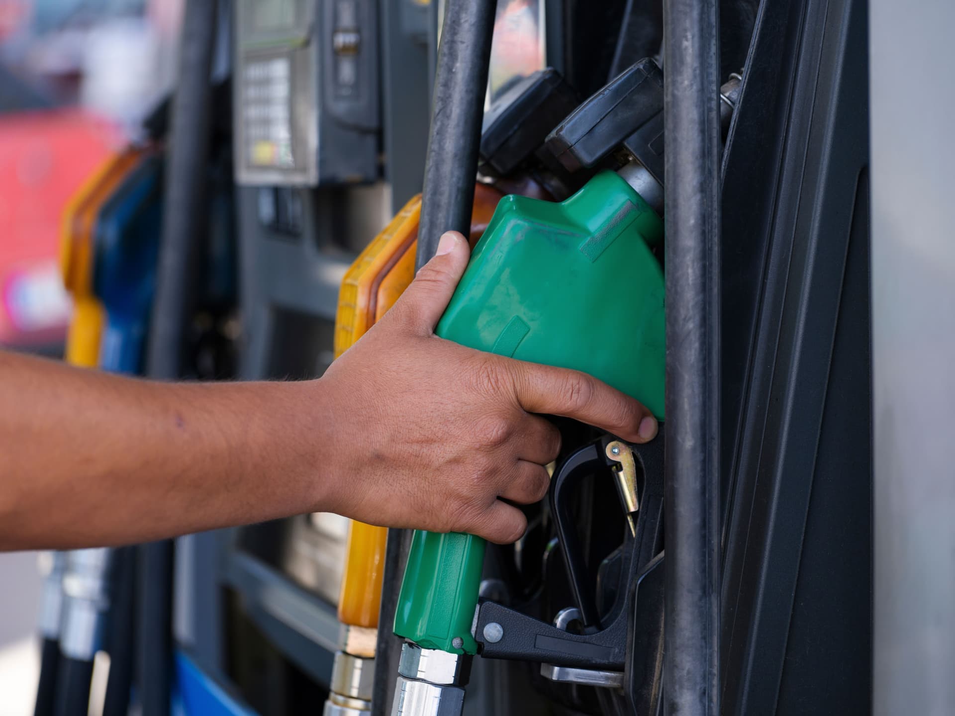 A hand holding a fuel pump nozzle
