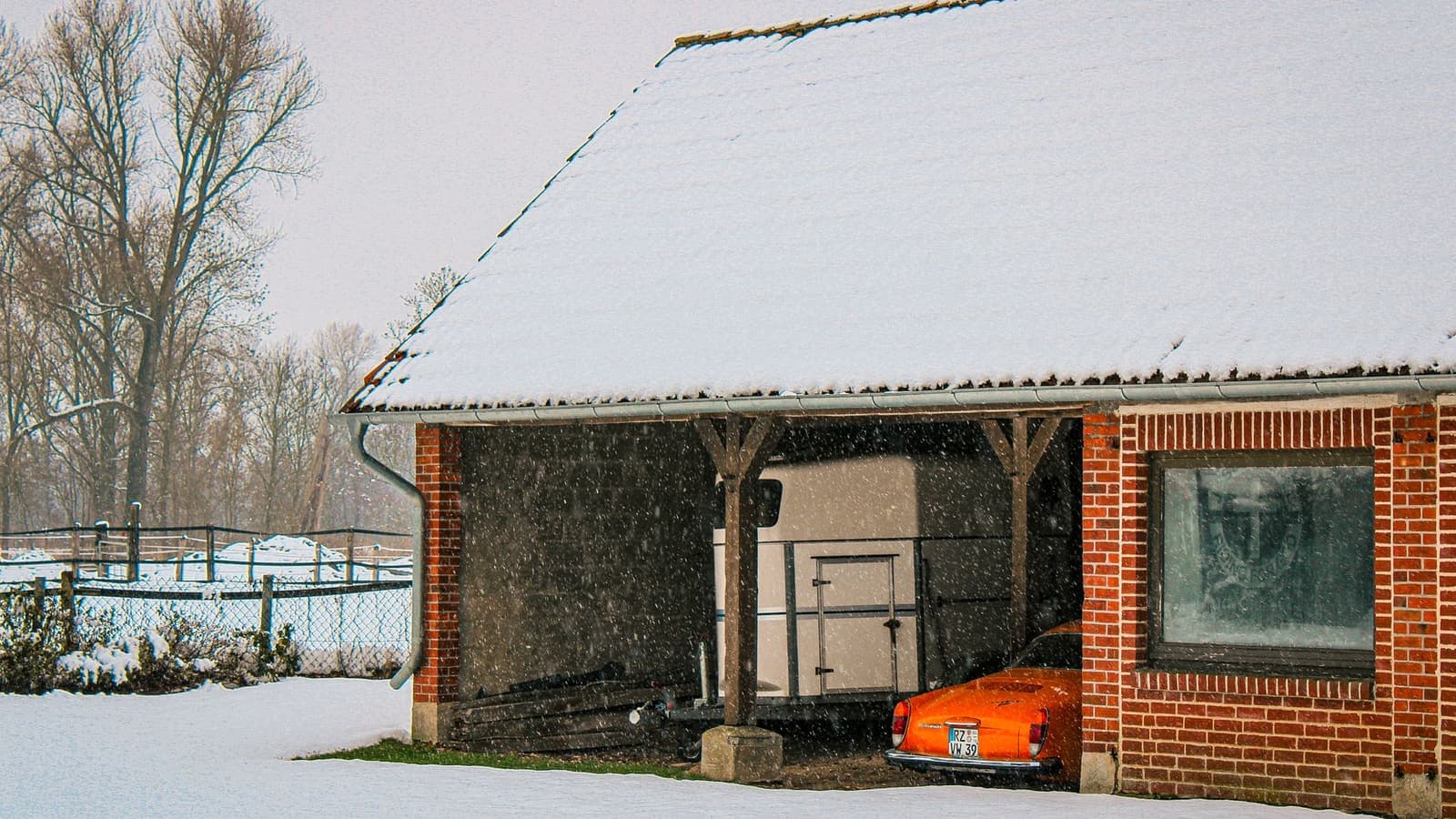 A car parked in a garage during winter snowfall