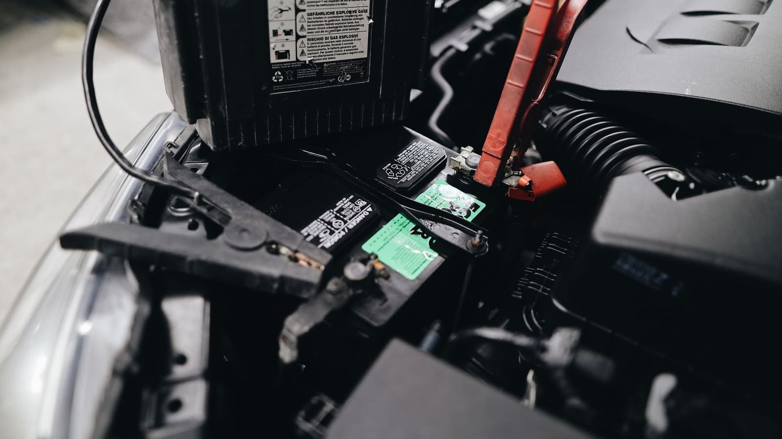 Jumper clamps attached to a car battery in an engine bay