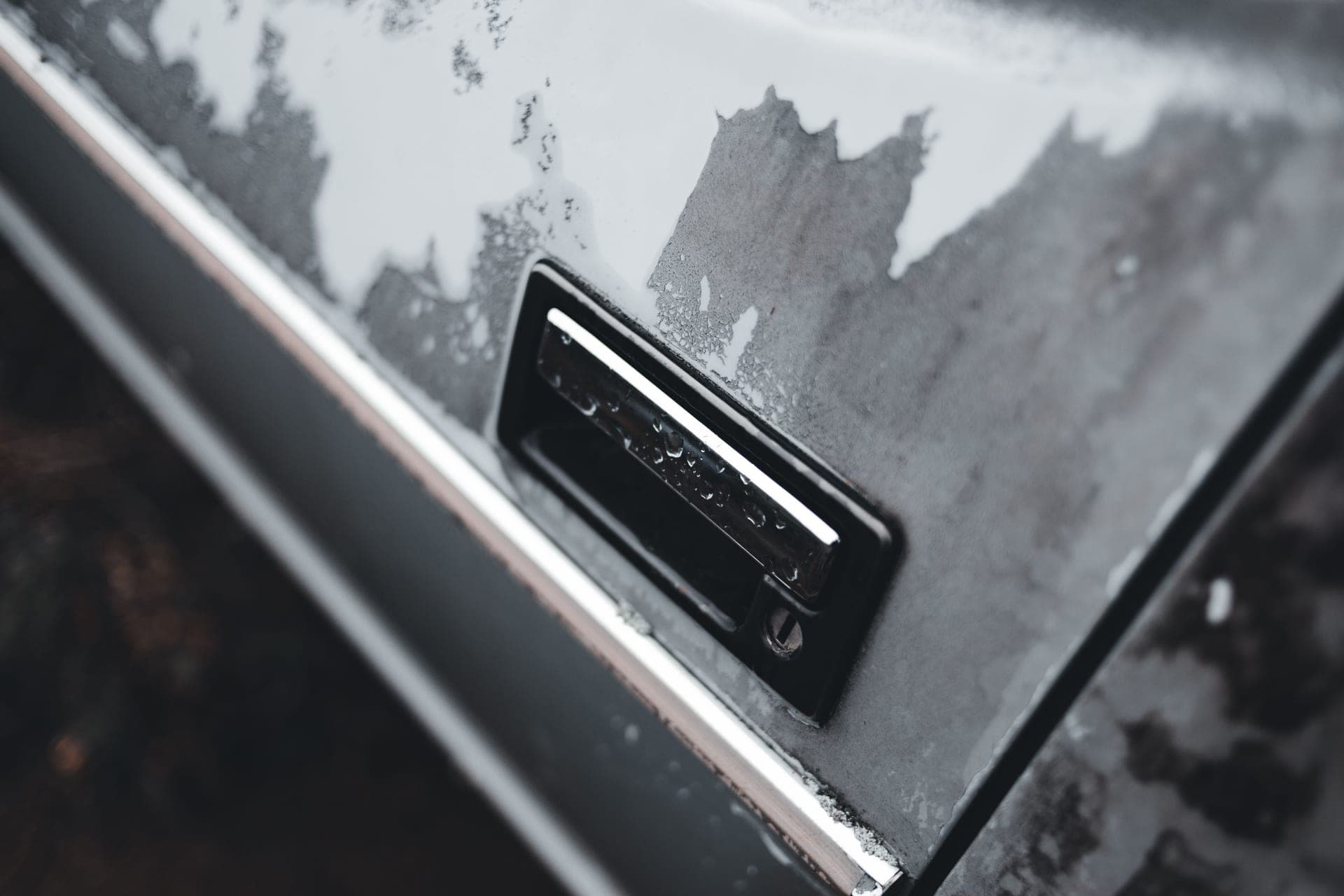 A weathered car door and lock in cold weather