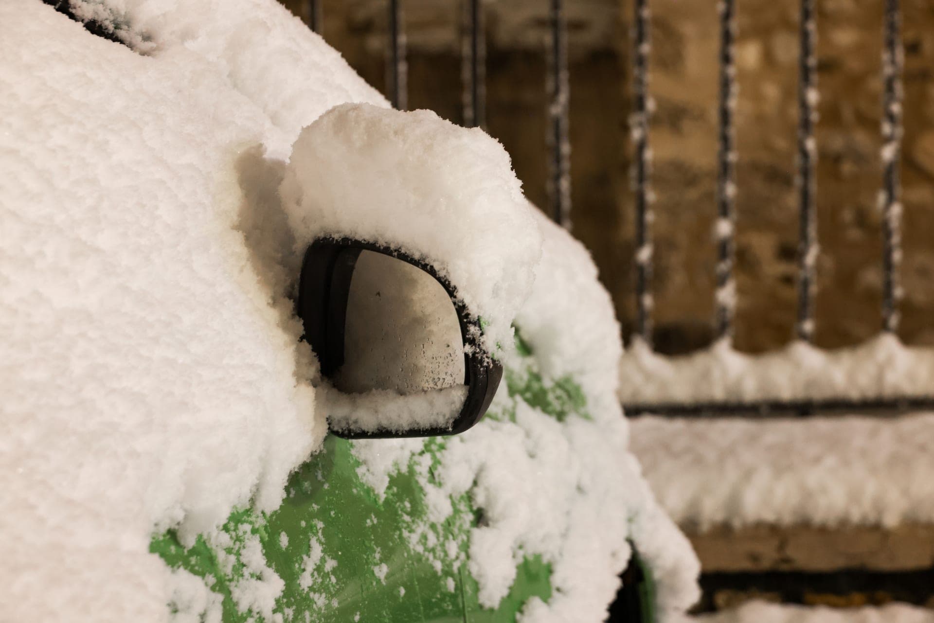 A car side mirror covered in overnight snow and ice