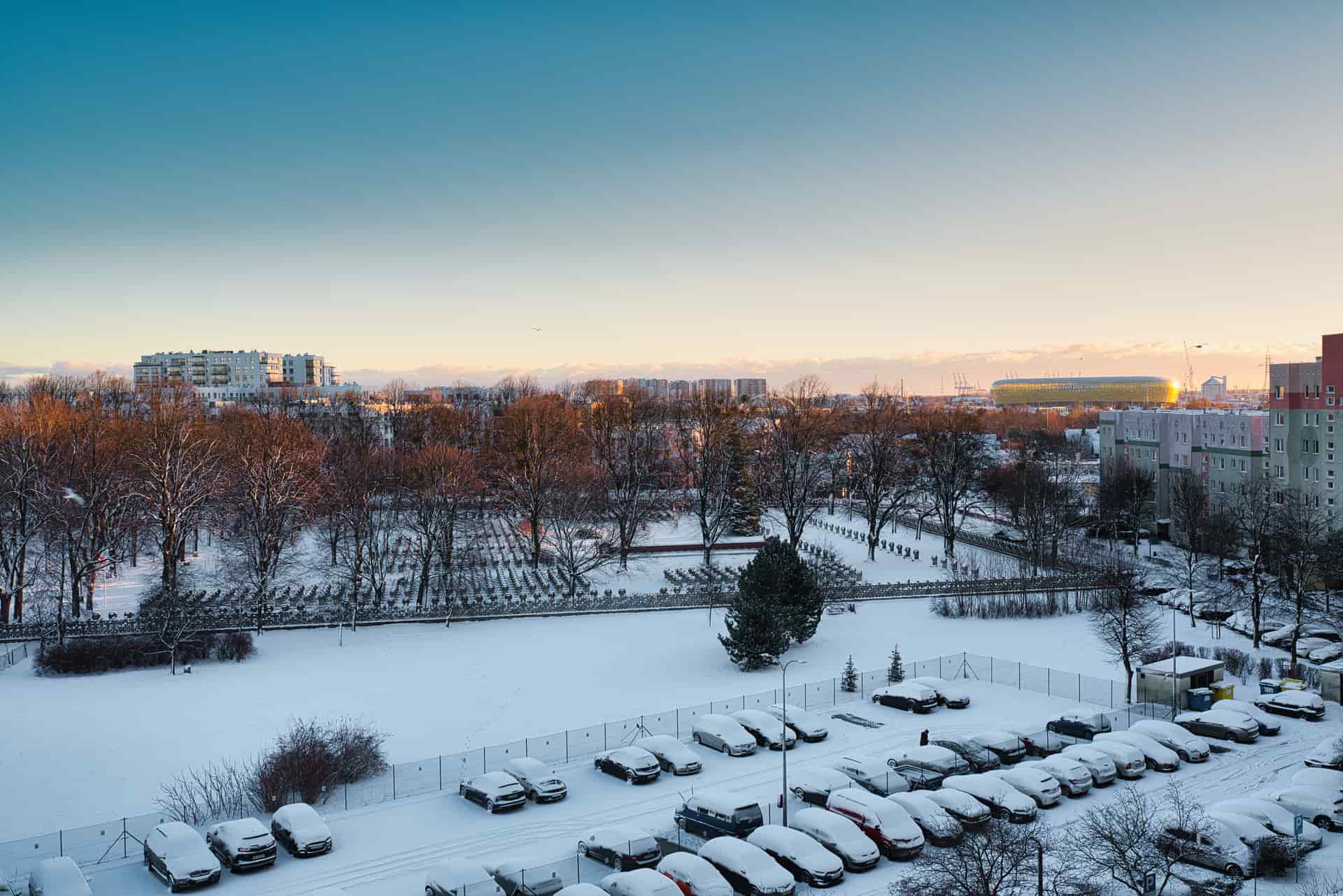 Snow-covered ground and vehicles under a low winter sun