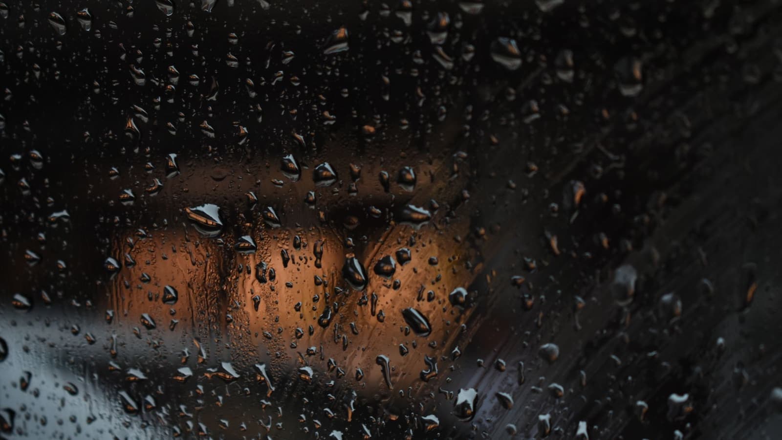 Rain droplets beaded on a car window at night