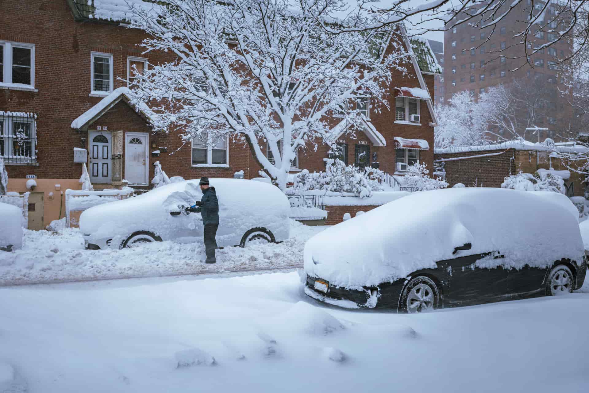 Snow being cleared from a vehicle in a residential street