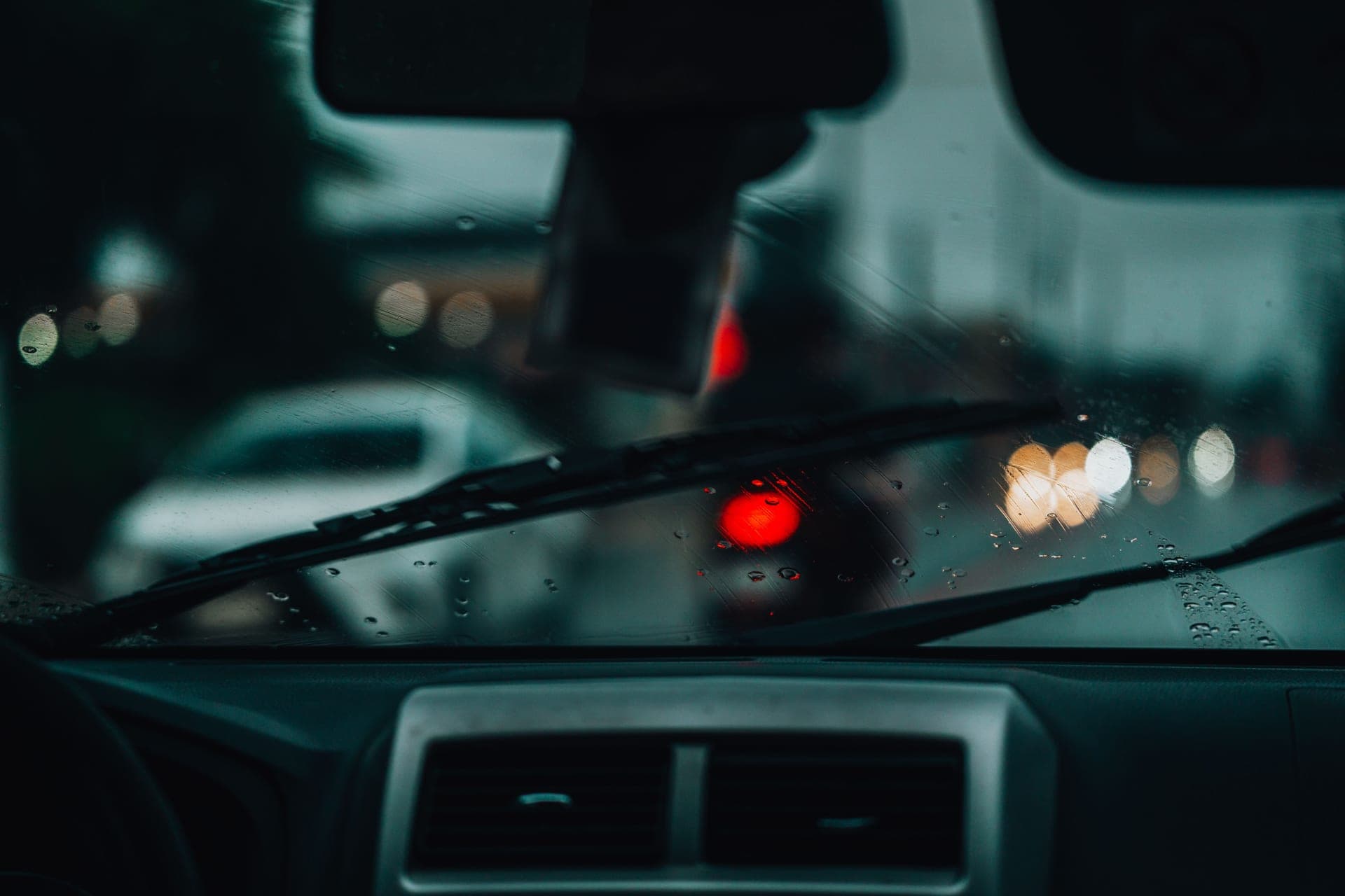 Rain beading on a car window at night