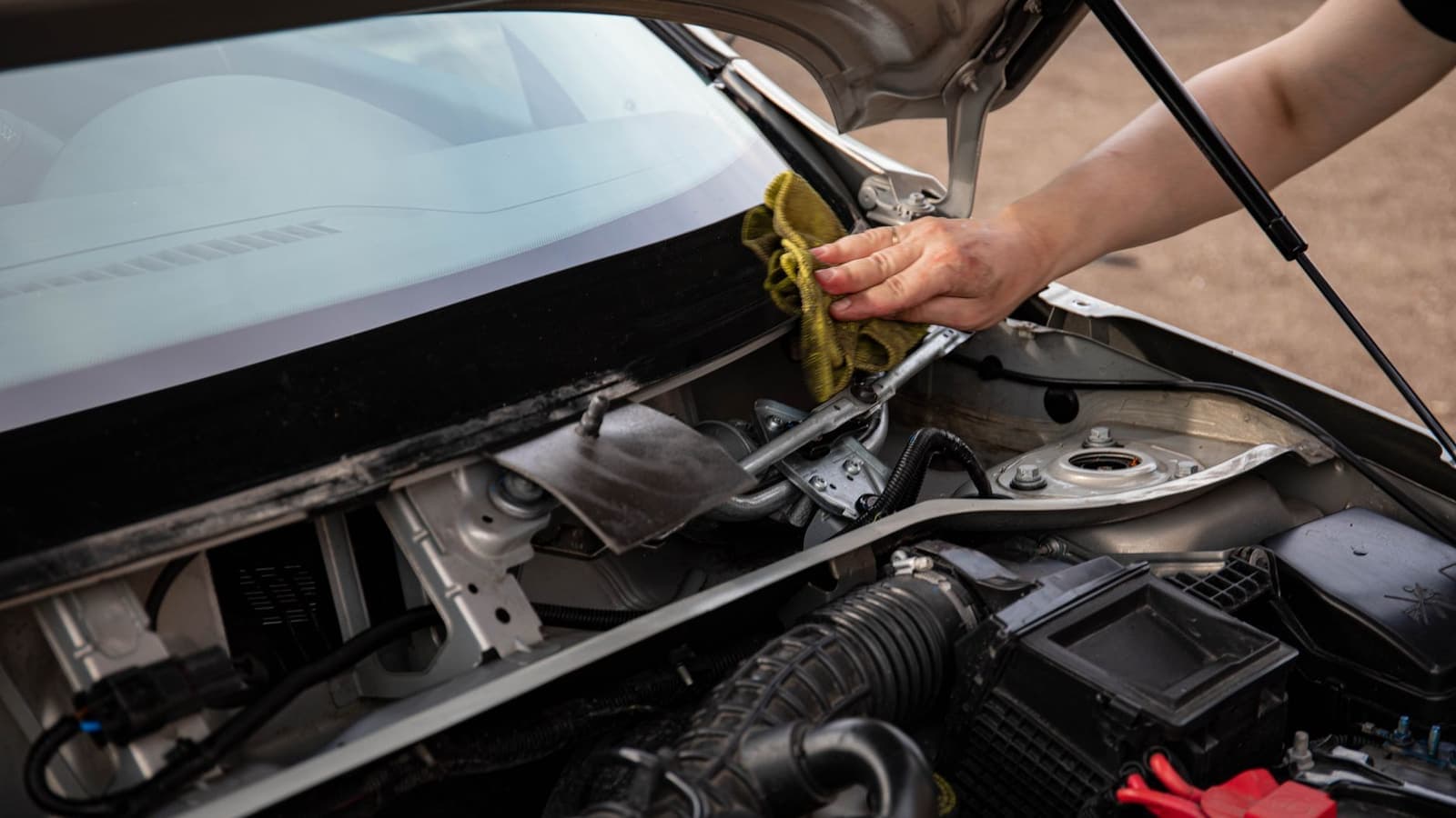 A person wiping a car windshield with a cloth